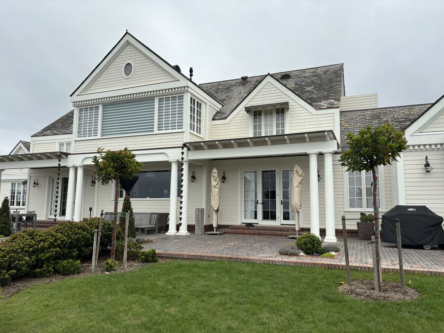 Large traditional home exterior painted white with brick patio